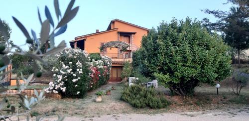 uma casa laranja com árvores e flores em frente em APPARTAMENTI DOLCETURISMO FONTECAIME...RELAX... em Bevagna