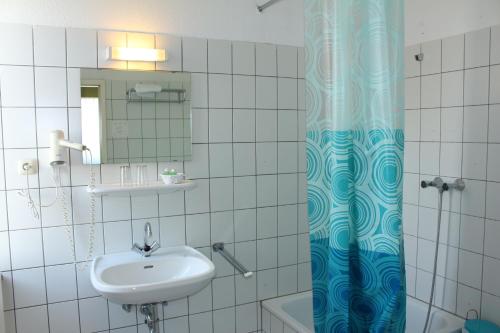 a bathroom with a sink and a shower curtain at Hotel-Restaurant Heute in Frechen