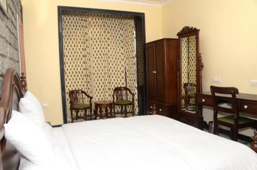 a bedroom with a bed and a desk and chairs at The Fateh Pratap Hotel & Resort in Sheoganj