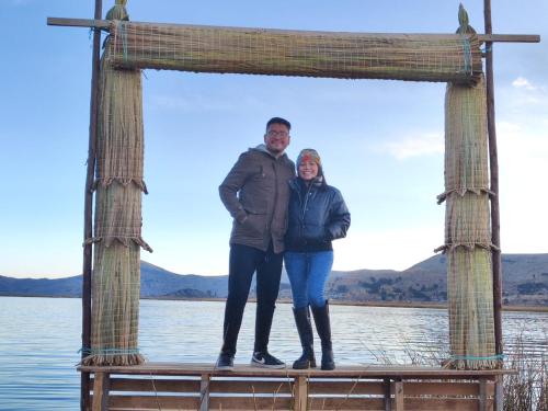 a man and a woman standing on a wooden frame over the water at TITICACA JALTAWI LODGE in Puno