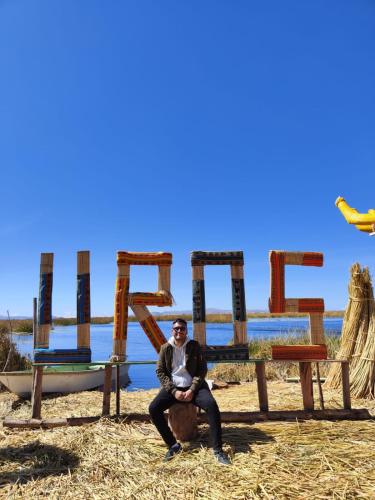 a man sitting in front of a sign in front at TITICACA JALTAWI LODGE in Puno