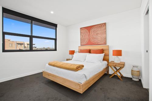 a white bedroom with a bed and a window at Astra Apartments Wollongong Beatson Street in Wollongong