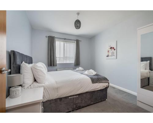 um quarto com uma cama com lençóis brancos e uma janela em Central Belfast Apartments: Cromwell em Belfast