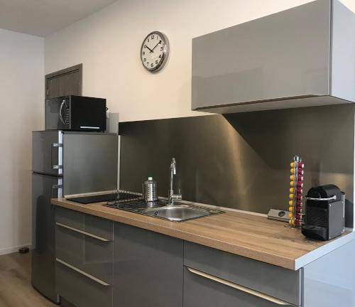 a kitchen with a sink and a clock on the wall at Studio Port Moderne HyperCentre Lumineux Climatisé in Toulon