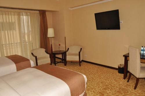 a hotel room with two beds and a flat screen tv at Capital Hotel and Spa in Addis Ababa