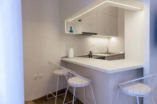 een keuken met 3 barkrukken en een aanrecht bij Cozy Studio In The Heart of City in Komotini