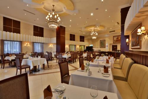 ein Restaurant mit weißen Tischen, Stühlen und Kronleuchtern in der Unterkunft Capital Hotel and Spa in Addis Abeba