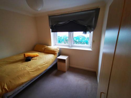 a small bedroom with a bed and a window at Town Centre Penthouse in Basingstoke