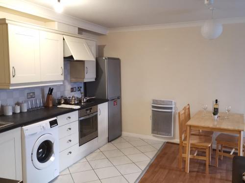 a kitchen with white cabinets and a table with a dining room at Town Centre Penthouse in Basingstoke