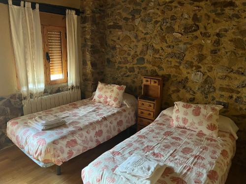 2 Betten in einem Zimmer mit einer Steinmauer in der Unterkunft Casa Rural El Medico in Serradilla del Arroyo