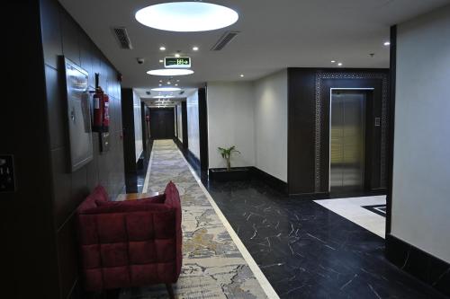 a hallway with a red chair in a building at Aster Hotel in Jeddah