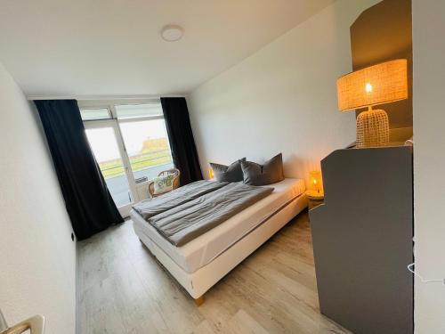 a bedroom with a bed and a large window at Apartment Eerste Reeg für 2-4 Personen mit Pool in Dahme