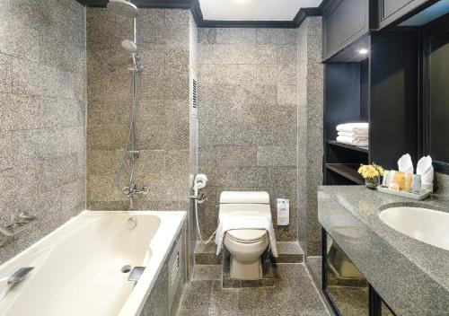 a bathroom with a tub and a toilet and a sink at Grand President Bangkok in Bangkok