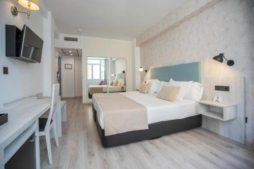 a hotel room with a large bed and a desk at Soho Boutique Bahía Málaga in Málaga