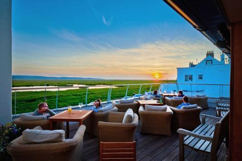 a patio with tables and chairs on a deck with the sunset at The Ship in Parkgate