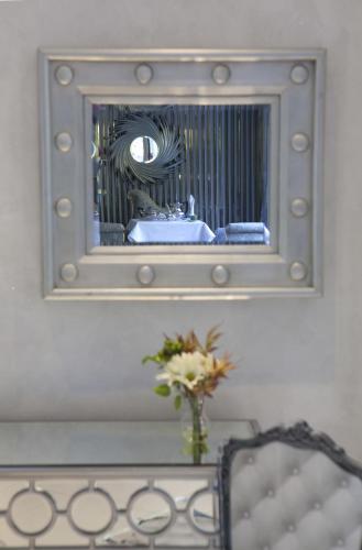 a mirror on a wall with a vase of flowers at Garden Spa Boutique Hotel in Skopje
