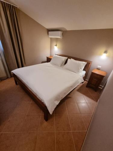 a bedroom with a large bed with white sheets and pillows at Villa Maslina in Ljubuški