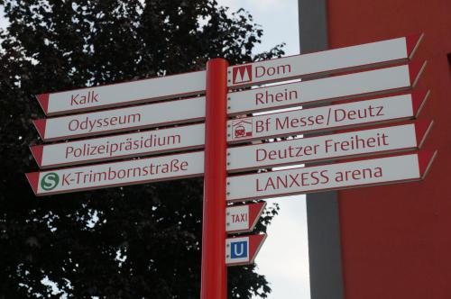 a red pole with street signs on it at Köln Deutz/Messe, Lanxess Arena in Cologne