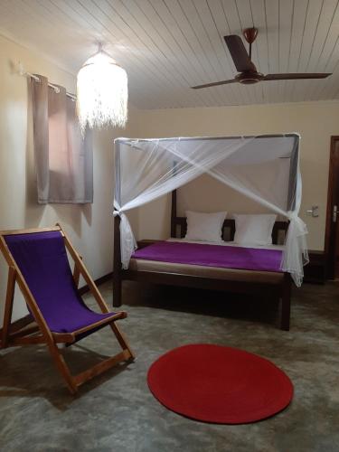 a bedroom with a bed and a chair and a rug at Le Moya Beach in Nosy Be