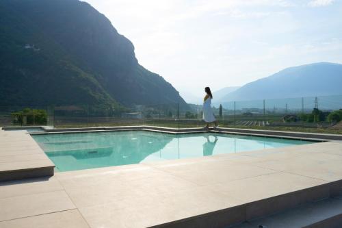 una mujer caminando por una piscina con montañas en el fondo en Art & Design Hotel Napura, en Bolzano