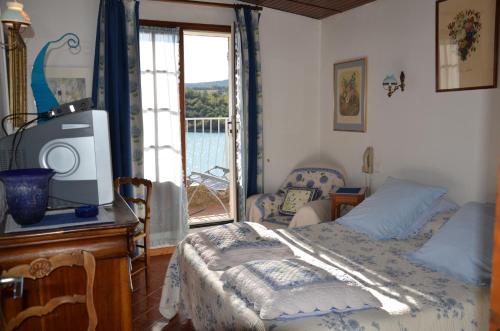 a bedroom with a bed and a tv and a window at Auberge du Lac in Bauduen