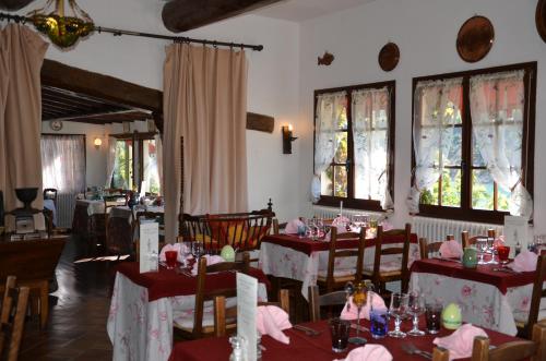 a dining room with tables and chairs and windows at Auberge du Lac in Bauduen