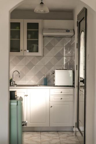 a kitchen with white cabinets and a microwave at Creta Vitalis in Kalathas