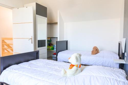 a bedroom with two beds with a stuffed dog sitting on the beds at Vacances pour 8 aux portes du Guilvinec in Plomeur