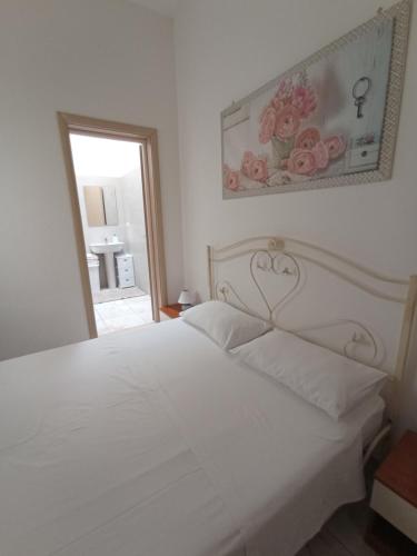 a bedroom with a white bed with a picture on the wall at B&B Lo Scrigno del Salento in Sava