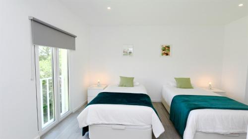 two beds in a room with white walls and windows at Marina Algarve-CleverDetails, located on the marina close to all main amenities in Vilamoura