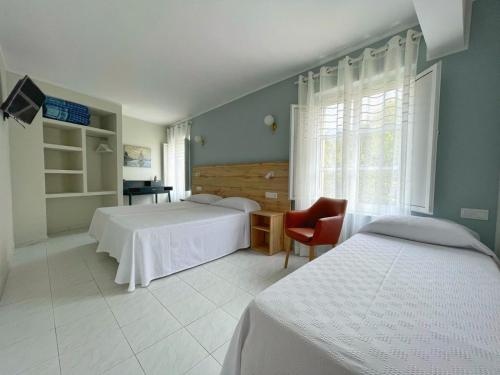 um quarto com 2 camas, uma cadeira e uma janela em Hotel Amadora - Admite mascotas em Barreiros