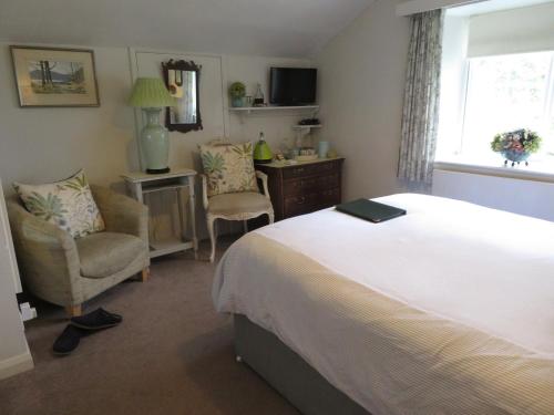 a bedroom with a bed and a chair and a desk at Slack Cottage in High Wray