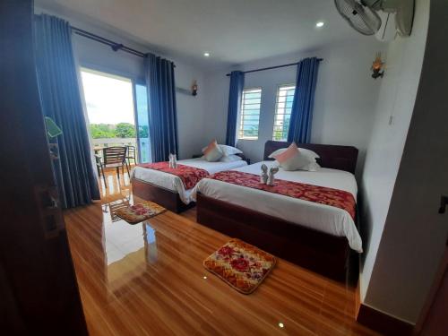 a hotel room with two beds and a balcony at Realkhom Homestay in Siem Reap