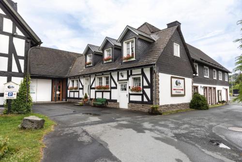 een huis met een zwart-wit gebouw bij Gästehaus Schwarzenauer Mühle in Bad Berleburg