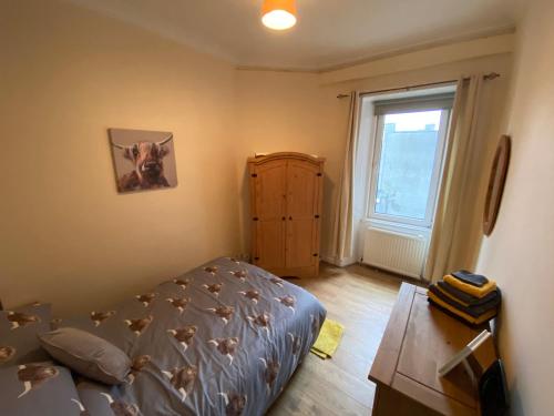 - une chambre avec un lit, une commode et une fenêtre dans l'établissement Dalblair Apartment, à Ayr