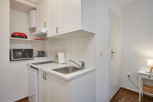cocina blanca con fregadero y microondas en Studio apartment Tramonto, en Cavtat
