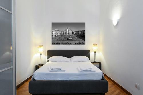 a bedroom with a bed with white sheets and two lamps at Charming San Babila Apt. in Milan