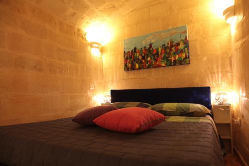 1 dormitorio con 1 cama con 2 almohadas y una pintura en La Conchiglia Nei Sassi, en Matera