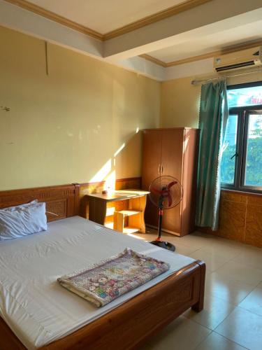 a bedroom with a bed and a desk and a window at Nhà nghỉ FAMY in Móng Cái