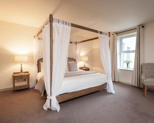 a bedroom with a canopy bed and a window at Comis Hotel & Golf Resort in Douglas