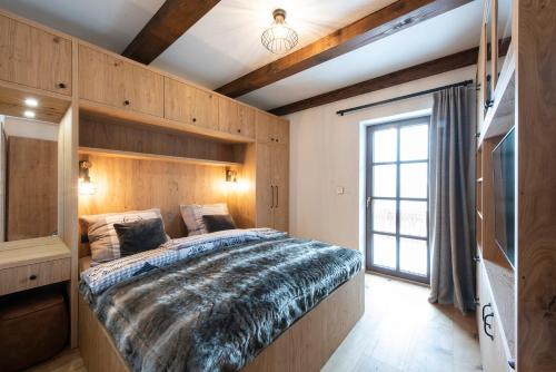 um quarto com uma cama grande e uma janela em Wellness apartmán Kvilda em Kvilda