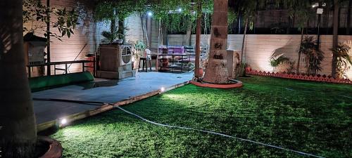 a room with a green lawn with a hose at The Homeland Stay in Ahmedabad