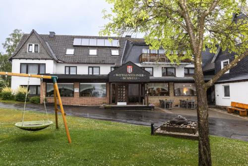 un hotel con parque infantil frente a un edificio en Pension Wittgensteiner Schweiz en Bad Berleburg
