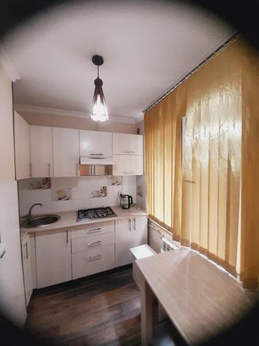a kitchen with white cabinets and a table in it at Family apartment 7 in Shymkent