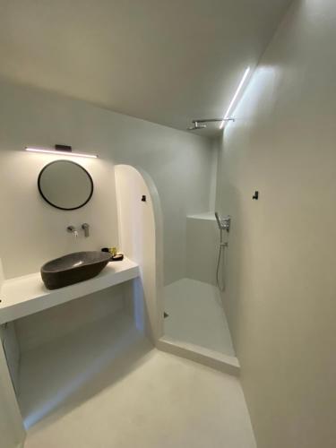 a white bathroom with a sink and a mirror at Artelie apartment in Kyparissia