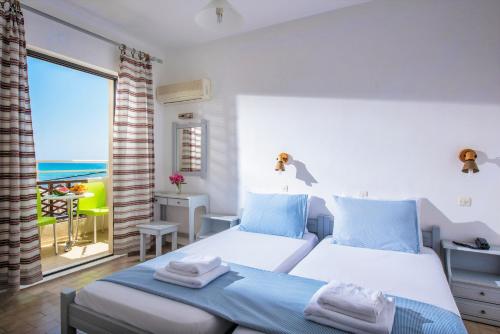 a bedroom with a bed with a view of the ocean at Smaragdine Beach Hotel in Stalís