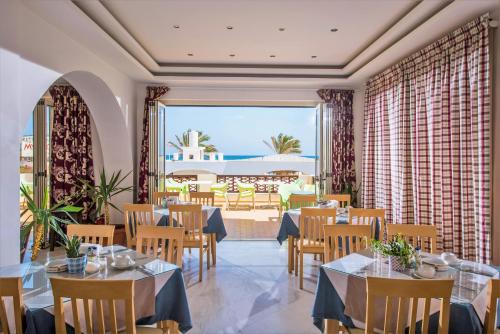 a restaurant with tables and chairs and a large window at Smaragdine Beach Hotel in Stalís