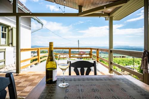 a bottle of wine and a glass on a table on a balcony at NemCsuri Vendegház Somló in Somlóvásárhely