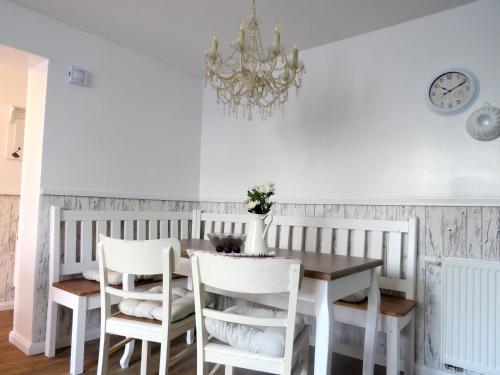 a dining room table with white chairs and a chandelier at Gut Brüggen in Kerpen