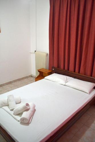 a bed with towels on it with a red curtain at Studio Lantzos in Oreoi